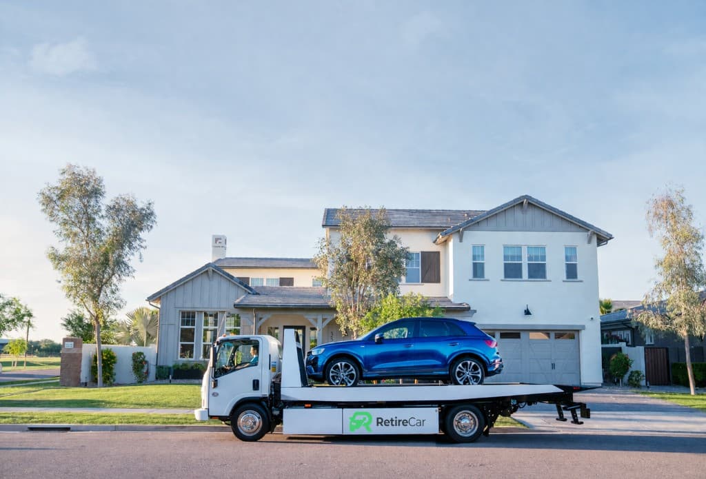 RetireCar flatbed truck picking up a vehicle at a home
